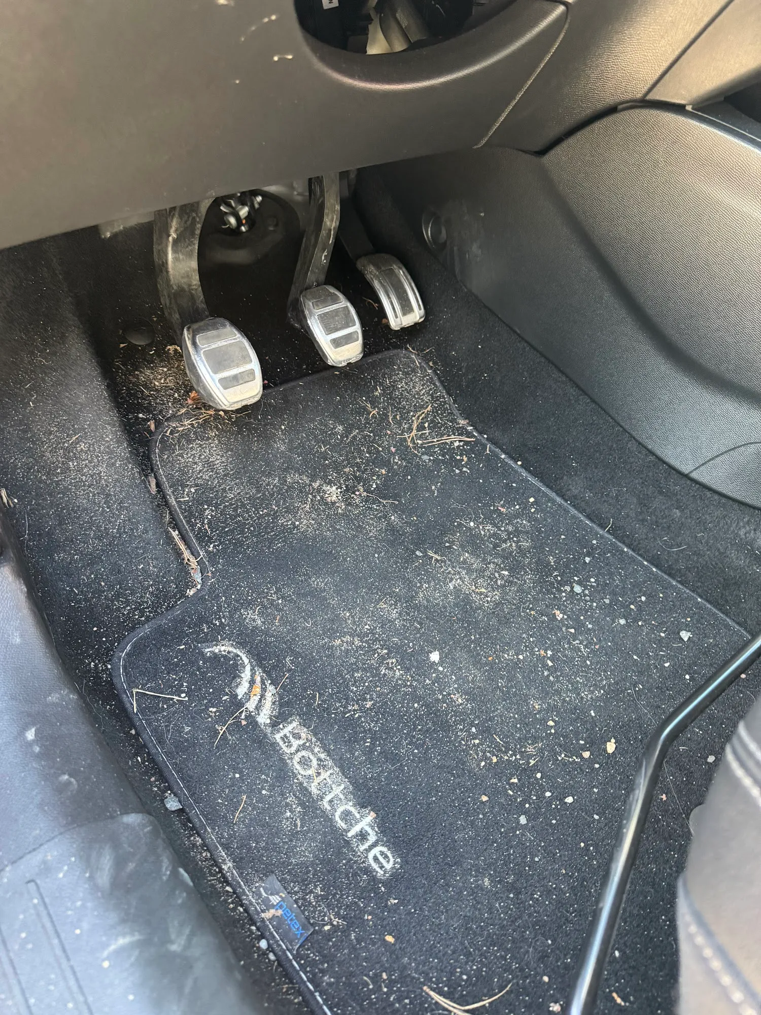 Stark verschmutzter Fußraum mit Fußmatte und Pedalen vor der Aufbereitung